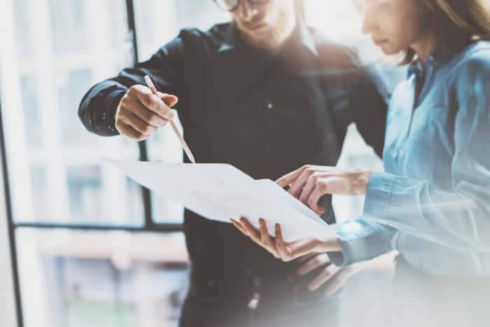 un homme qui pointe un document avec un stylo
