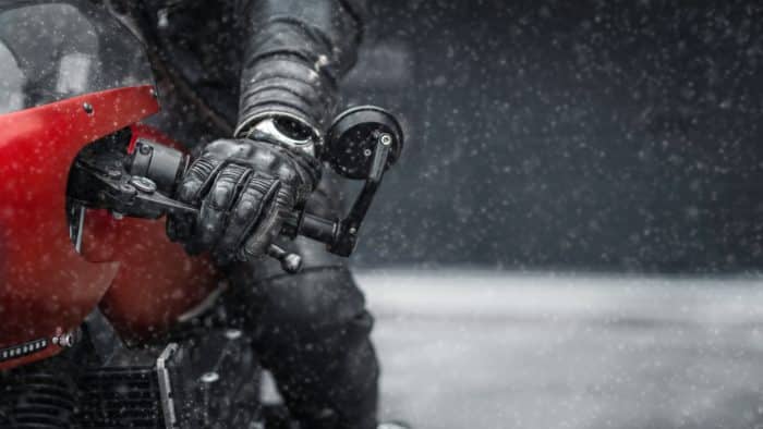 main de motard avec un gant et une moto rouge sous la pluie