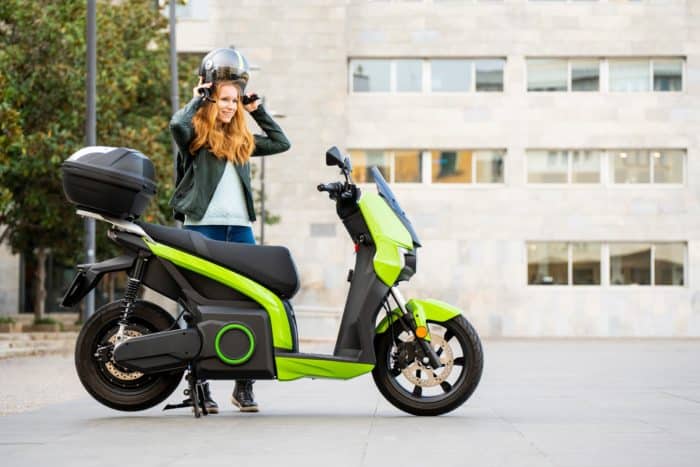 Femme avec casque et scooter électrique vert