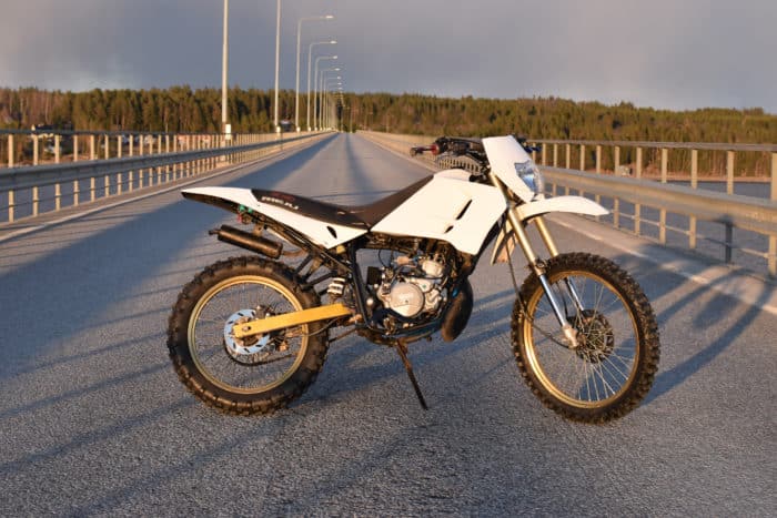 moto 50 cc blanche garée sur la route 