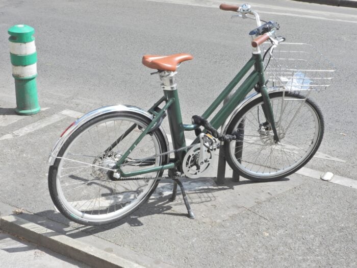 V&eacute;lo vintage vert attach&eacute; dans la rue en toute s&eacute;curit&eacute; &agrave; un arceau d&eacute;di&eacute; avec un antivol pour v&eacute;lo 